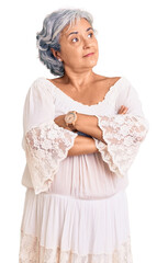 Senior woman with gray hair wearing bohemian style looking to the side with arms crossed convinced and confident