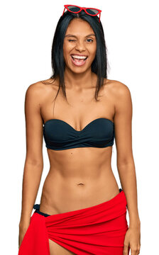 Young african american woman wearing bikini winking looking at the camera with sexy expression, cheerful and happy face.