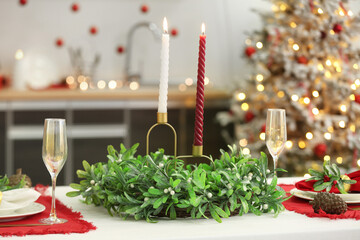 Table setting with Christmas mistletoe wreath in kitchen, closeup