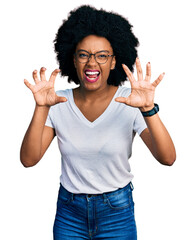 Young african american woman wearing casual white t shirt smiling funny doing claw gesture as cat,...