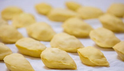 Verenik, pierogi, pierogui, perohê, Ukrainian food closeup on wooden table with wheat flour and rolling pin. 