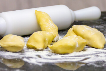 Verenik, pierogi, pierogui, perohê, Ukrainian food closeup on wooden table with wheat flour and rolling pin. 