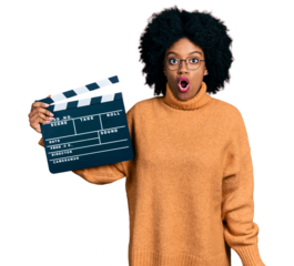 Young african american woman holding video film clapboard scared and amazed with open mouth for surprise, disbelief face