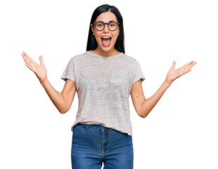 Beautiful young woman wearing casual clothes and glasses celebrating victory with happy smile and winner expression with raised hands