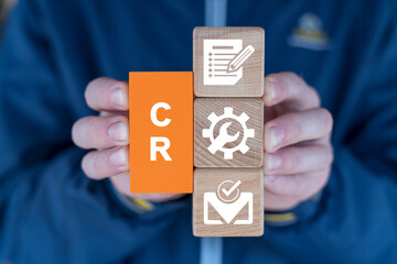 Man holding multi-colored blocks with icons sees on a orange block the abbreviation: CR. Change...