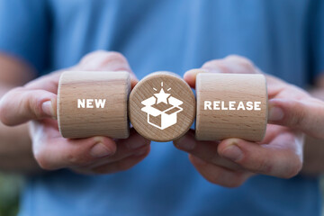 Man holding wooden blocks sees inscription: NEW RELEASE. New release concept. New product development. Coming soon announce. Update product version. - obrazy, fototapety, plakaty