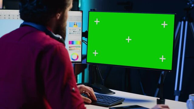 Photographer using advanced photo editing software on green screen monitor to make improvement to images quality. Photo editor utilizing specialized photographs retouching application on mockup PC