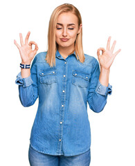 Beautiful caucasian woman wearing casual denim jacket relax and smiling with eyes closed doing meditation gesture with fingers. yoga concept.