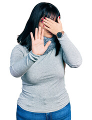 Young hispanic plus size woman wearing winter scarf covering eyes with hands and doing stop gesture with sad and fear expression. embarrassed and negative concept.
