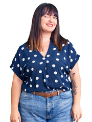 Fototapeta premium Young plus size woman wearing casual clothes winking looking at the camera with sexy expression, cheerful and happy face.