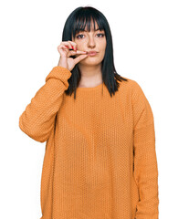 Young hispanic woman wearing casual clothes mouth and lips shut as zip with fingers. secret and...