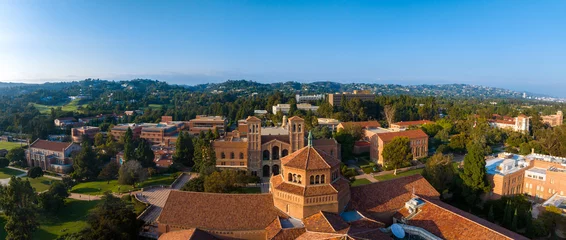 Fototapeten Aerial view of UCLA campus in Westwood, Los Angeles, featuring red-brick, Gothic, and modern buildings amidst green lawns and trees on a sunny day. © ingusk