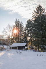 Old farm in the countryside at winter covered with snow at sunset.