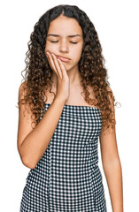 Teenager hispanic girl wearing casual clothes touching mouth with hand with painful expression because of toothache or dental illness on teeth. dentist