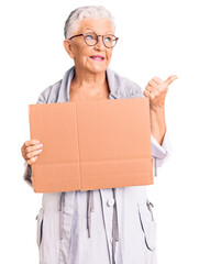 Senior beautiful woman with blue eyes and grey hair holding we need a change banner pointing thumb up to the side smiling happy with open mouth