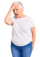 Senior beautiful woman with blue eyes and grey hair wearing casual white tshirt surprised with hand on head for mistake, remember error. forgot, bad memory concept.