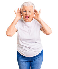 Senior beautiful woman with blue eyes and grey hair wearing casual white tshirt trying to hear both hands on ear gesture, curious for gossip. hearing problem, deaf