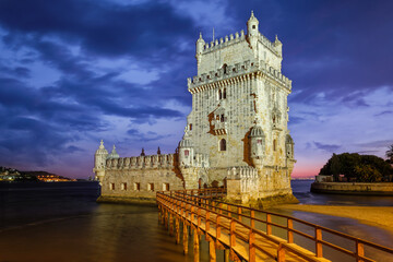 Fototapeta na wymiar Belem Tower or Tower of St Vincent - famous tourist landmark of Lisboa and tourism attraction - on the bank of the Tagus River (Tejo) after sunset in dusk twilight with dramatic sky. Lisbon, Portugal