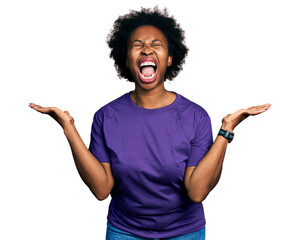 African american woman with afro hair wearing casual purple t shirt celebrating mad and crazy for...