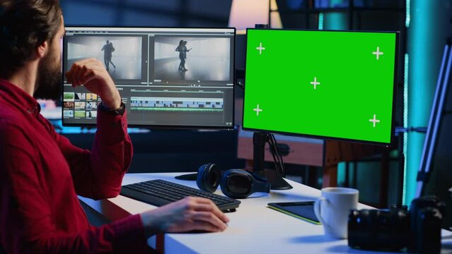 Video editor trimming segments of drone shot footage, using green screen PC monitor to work. Videographer splicing film pieces, editing them using professional software on mockup computer display