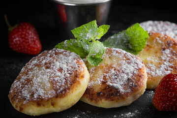 Cottage cheese pancakes with mint and sour cream, strawberries and powder