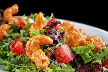 Salad with shrimp in batter, herbs and tomatoes on a plate