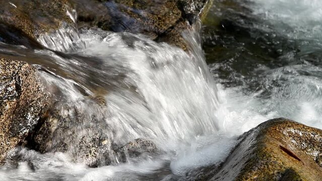 Small mountain stream cascade falling over river rock creating whitewater in closeup view of motion