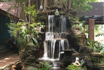 Waterfall is decorated with a small Buddha statue. At Wat Tha Mai temple. Located at Samut Sakhon Province in Thailand.