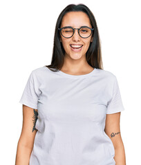 Young hispanic woman wearing casual white t shirt winking looking at the camera with sexy expression, cheerful and happy face.