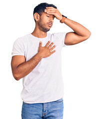 Young latin man wearing casual clothes touching forehead for illness and fever, flu and cold, virus sick