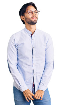 Handsome hispanic man wearing business shirt and glasses smiling looking to the side and staring away thinking.