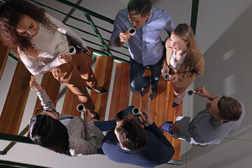 Obraz na płótnie Canvas Group of coworkers talking during coffee break on stairs in office, top view