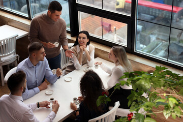 Group of coworkers having coffee break in cafe, above view - Powered by Adobe