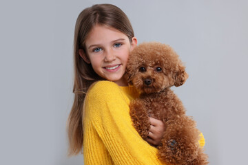 Little child with cute puppy on light grey background. Lovely pet