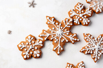 Christmas background with gingerbread snowflakes cookies decorated with white royal icing over white background, top view. Flat lay.