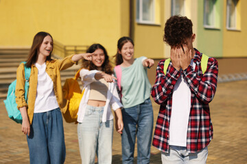 Teen problems. Group of students pointing at upset boy outdoors, selective focus