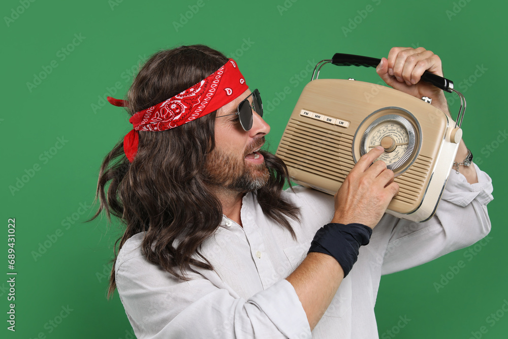 Sticker Stylish hippie man in sunglasses with retro radio receiver on green background