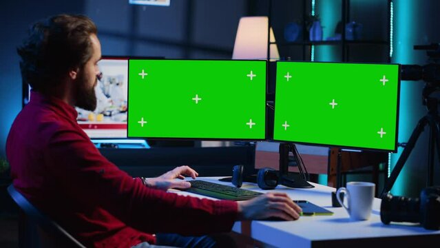 Photographer using photo editing software on Chroma key multi monitors setup to improve images quality. Photo editor utilizing pictures retouching application on green screen display