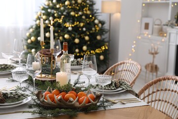 Christmas table setting with festive decor and dishware in room