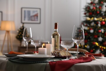 Christmas table setting with burning candles, appetizers and dishware in room