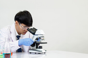Portrait Asian man student scientist Wearing a doctor gown in the lab looking hand at chemist. caused by mixing reagents in scientific research laboratories with test tubes and microscope on the table
