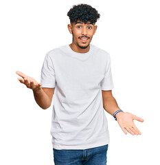 Young arab man wearing casual white t shirt smiling cheerful with open arms as friendly welcome, positive and confident greetings