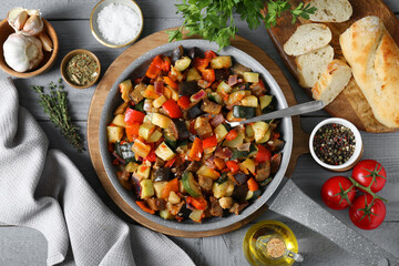 Delicious ratatouille and ingredients on grey wooden table, flat lay