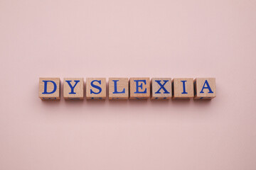 Wooden cubes with word Dyslexia on beige background, flat lay