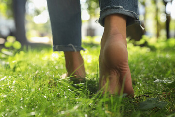 Woman walking barefoot on green grass outdoors, closeup - obrazy, fototapety, plakaty