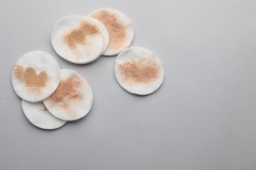 Dirty cotton pads after removing makeup on light grey background, flat lay. Space for text