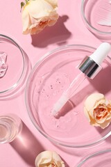 Bottle of cosmetic serum, flowers and petri dishes with samples on pink background, flat lay