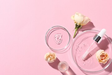 Bottle of cosmetic serum, flowers and petri dishes with samples on pink background, flat lay. Space for text