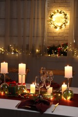 Christmas table setting with burning candles and festive decor