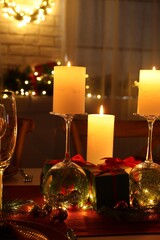 Christmas celebration. Burning candles, glasses and festive decor on table